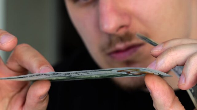 counterfeit money.
Checking the watermark on cash.
Banknote without a watermark.
Fake money in the hands of a guy.
A deceived person looks at a piece of paper that looks like money