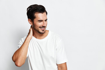 Smiling man wearing casual white t-shirt looking to side with a joyful expression while standing...