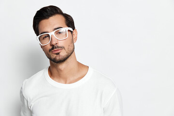 Stylish confident young man wears casual white t-shirt and stylish white glasses, looking at the...