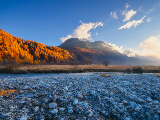 Nature. Mountain river at dawn. Bright sky and clouds. Pebbles on the river bank. Incredible view...