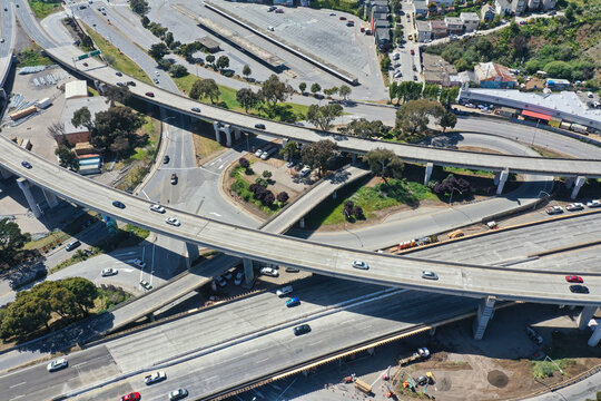 Aerial view of a complex highway interchange system with multiple overpasses and underpasses bustling with vehicle traffic on a bright day, San Francisco, California, United States.