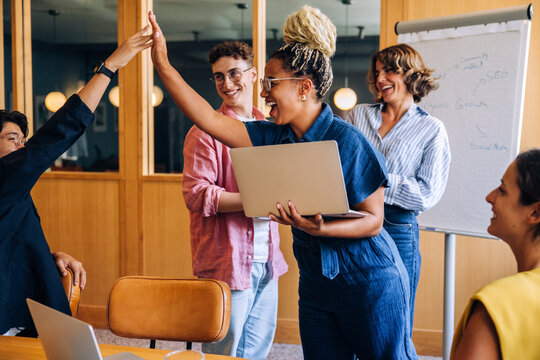 Professionals celebrating a successful discussion with a high five in an office setting
