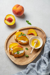 Toasted bruschetta with peach, nectarine, cream cheese or ricotta and honey on a wooden plate