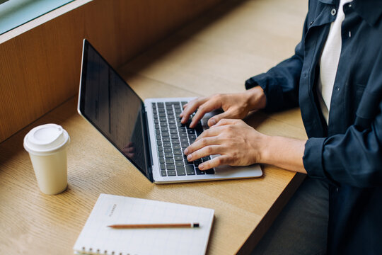 Person using a laptop at a desk with a coffee cup and notebook - Powered by Adobe