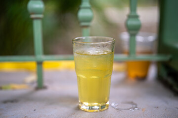 Refreshing yellow drink in a glass with ice on a summer day.