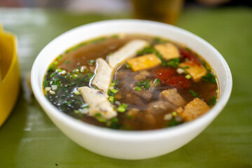 Delicious bowl of savory soup with meat, herbs, and vibrant toppings.