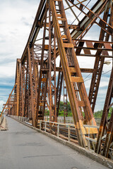 Rusty iron bridge with intricate design and cloudy sky