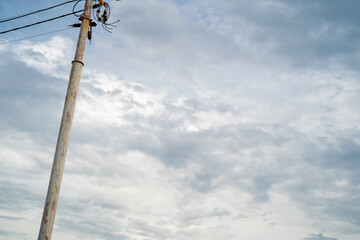 A weathered utility pole against a cloudy sky.
