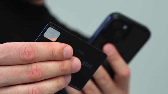 Online order and payment for goods using a credit card with money.
Money savings on a bank card of a man.
A guy with a mobile phone enters pinko d from a card