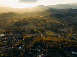 Aerial view of the dramatic Pai Canyon landscape bathed in golden sunlight, revealing the undulating terrain and distant mountains, Pai Canyon, Mae Hi, Thailand.