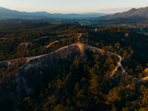 Aerial view of the rugged terrain of Pai Canyon under the warm glow of the setting sun, Mae Hi, Thailand.