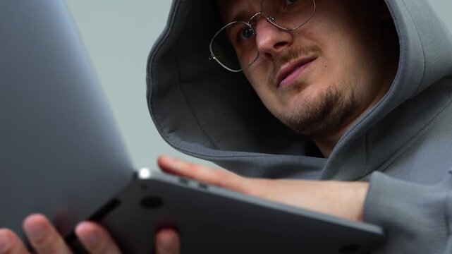 A hacker in a gray sweater enters electronic data to download the information he needs.
A young and smart hacker wants his online job.
A cyber specialist uses the Internet for work