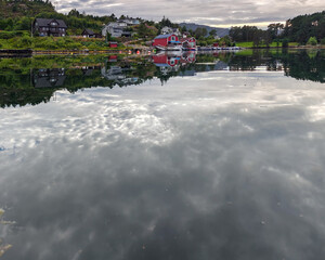 Amazing reflection of traditional norwegian houses in Vestrepollen Bay water, Norway