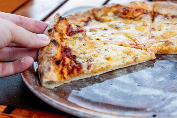 Visitor to pizzeria restaurant hold slice of italian Margherita pizza in hand