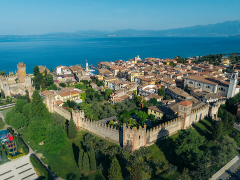 Aerial view of the Scaliger Castle and the historic town with its terracotta roofs, nestled by the serene blue waters of Lake Garda, Lazise, Veneto, Italy.