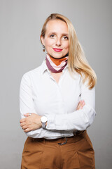 Confident businesswoman poses for a professional portrait with arms crossed at a neutral backdrop in a modern office setting