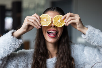 Young woman with lemon slices in a playful and witty pose indoors