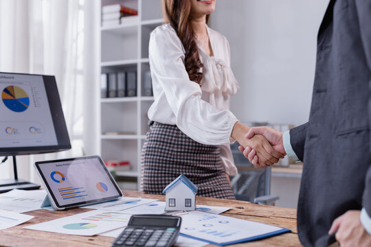 Businesswoman shaking hands with a client in a modern office, celebrating the successful signing of a real estate contract for a new home purchase, symbolizing partnership and trust