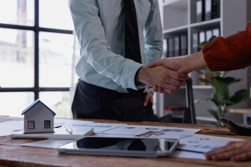 Real estate agent shaking hands with customer in the office after signing a contract for a new...