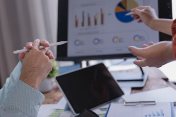 Business colleagues collaborating on a project, analyzing financial data on a monitor with a digital pen, discussing strategies and making informed decisions