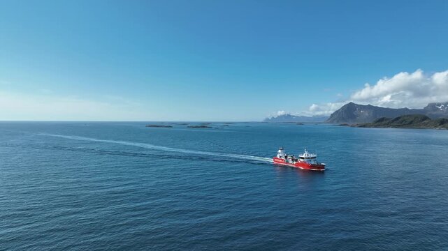 Aerial arc towards front of well boat carrying salmon or smolt on way to fish farm in Lofoten, Norway, near Gimsoy Island.