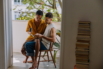 Male couple enjoying time together at home reading and relaxing