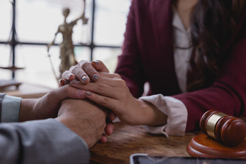 Female lawyer holding hands of client in a comforting gesture, showing empathy and support during...