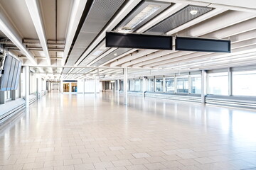 Brightly lit empty, large interior hallway inside international airport terminal. Wide angle view, natural window light, no people