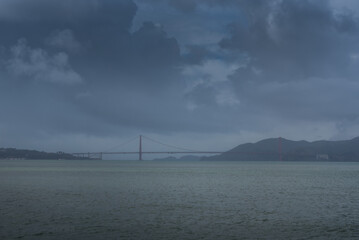 View of the Golden Gate Bridge shrouded in a dramatic, stormy sky, with dark waters reflecting the somber mood in San Francisco, California, United States.