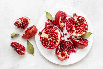 Plate full of fresh ripe pomegranate with cut in half and pieces, top view.