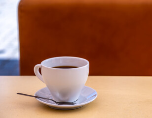 A white porcelain cup with coffee on the table.