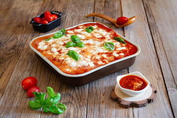 Delicious gnocchi alla sorrentina baking in a pan, surrounded by fresh ingredients