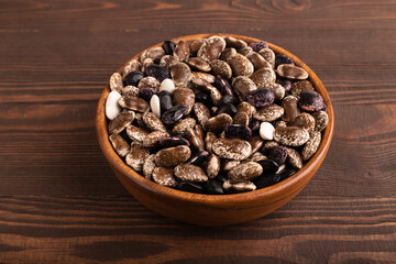 wooden bowl with Kidney beans on brown wooden, side view, close up