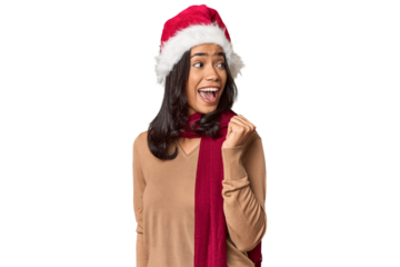 Filipino in Christmas attire and Santa hat points with thumb finger away, laughing and carefree.