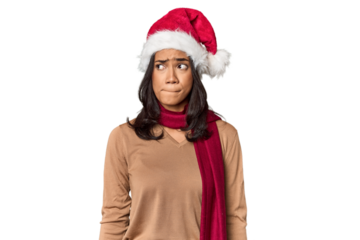 Filipino in Christmas attire and Santa hat confused, feels doubtful and unsure.