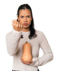 Young Filipina holding a pumpkin showing fist to camera, aggressive facial expression.