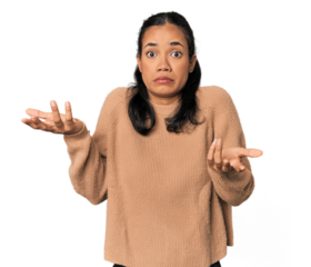 Young Filipina woman doubting and shrugging shoulders in questioning gesture.