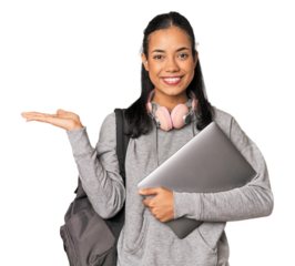 Young Filipino student with laptop showing a copy space on a palm and holding another hand on waist.