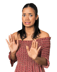 Young Filipino woman in studio rejecting someone showing a gesture of disgust.