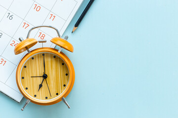 Alarm clock is on calendar with pencil, top view. Planning and time management concept