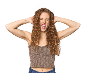 Simple redhead studio portrait covering ears with hands trying not to hear too loud sound.