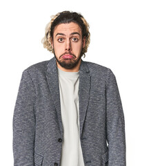 Young businessman in casual blazer shrugs shoulders and open eyes confused.