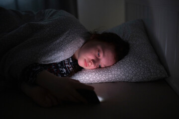 Girl using smart phone while lying on bed in bedroom