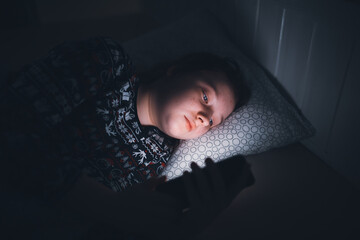 Girl using smart phone while lying on bed in bedroom