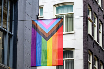 Colorful pride flag hanging between buildings, featuring rainbow colors, symbolizing diversity in...