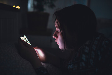 Girl using smart phone while lying on bed in bedroom