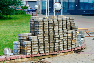 Restoration of sidewalk with paving stones stacked in piles, city infrastructure maintenance, replacement project for damaged walkway and urban construction. Paving slab replacement work in progress