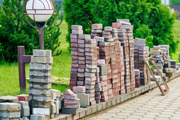 Paving stone repair and replacement with stacked slabs on sidewalk ready to restore and renovate damaged pedestrian pathway surface. Sidewalk repair process with paving slabs stacked in piles
