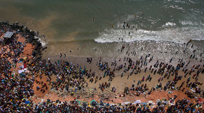 Puducherry, India - 28 February 2010: Aerial view of a multitude gathers along the sandy beach where the earth meets the sea in waves of foam.