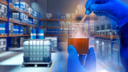 Chemical industry, laboratory, production. Hands in protective gloves analyze liquid in beaker with pipette inside industrial warehouse with chemical containers.